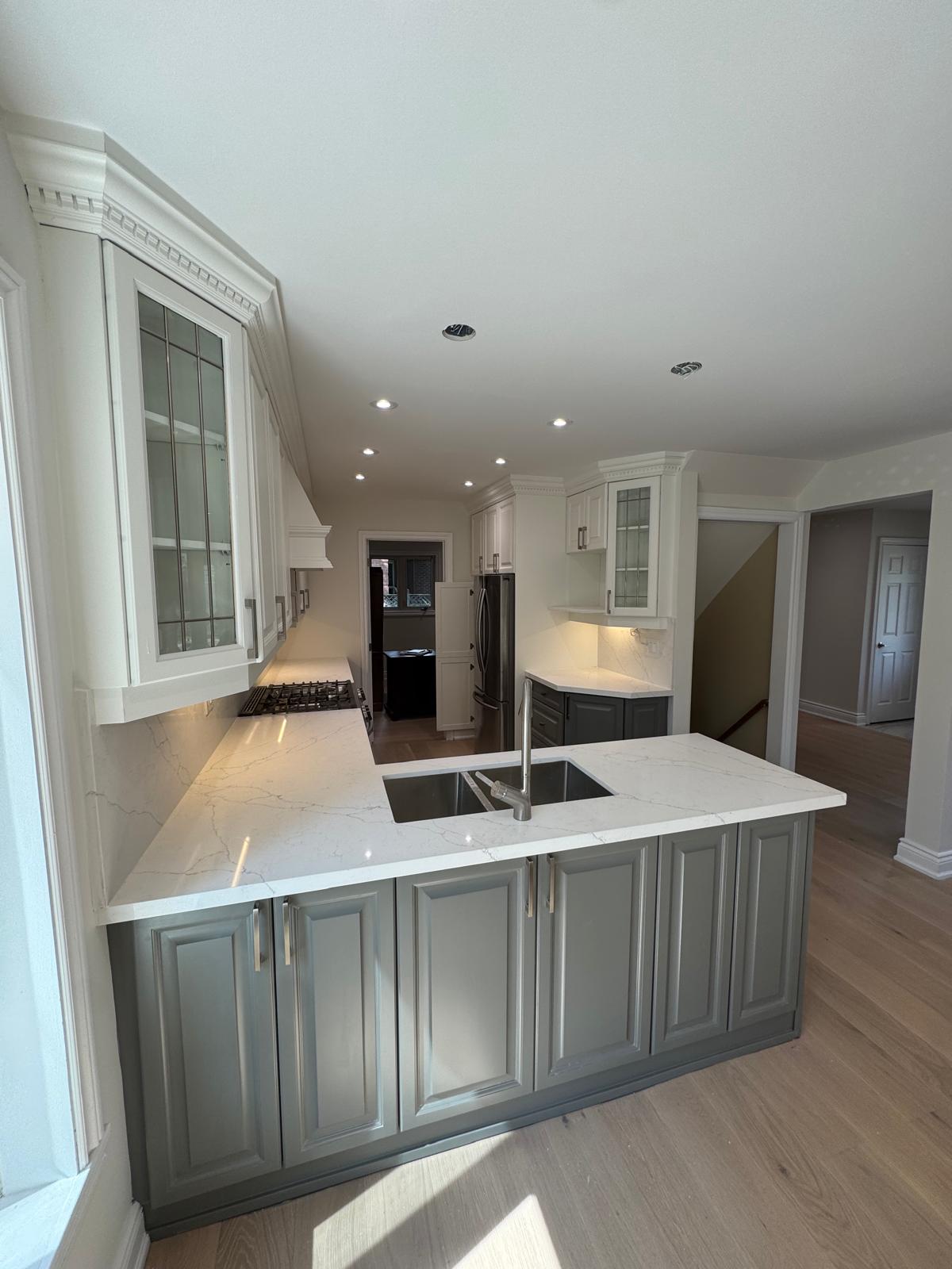Kitchen renovation in Aurora with white upper cabinets, grey base cabinets and a peninsula